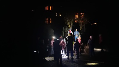 Večerní bojovka na zahradě s rozsvícenou knihovnou v pozadí